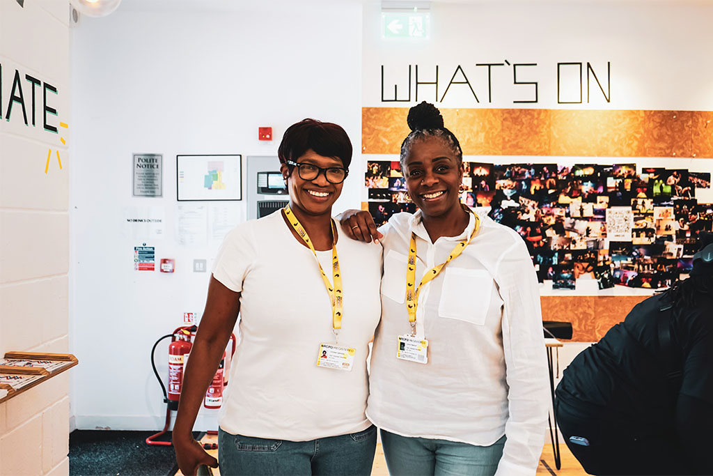 An image of two Black people stood together smiling.