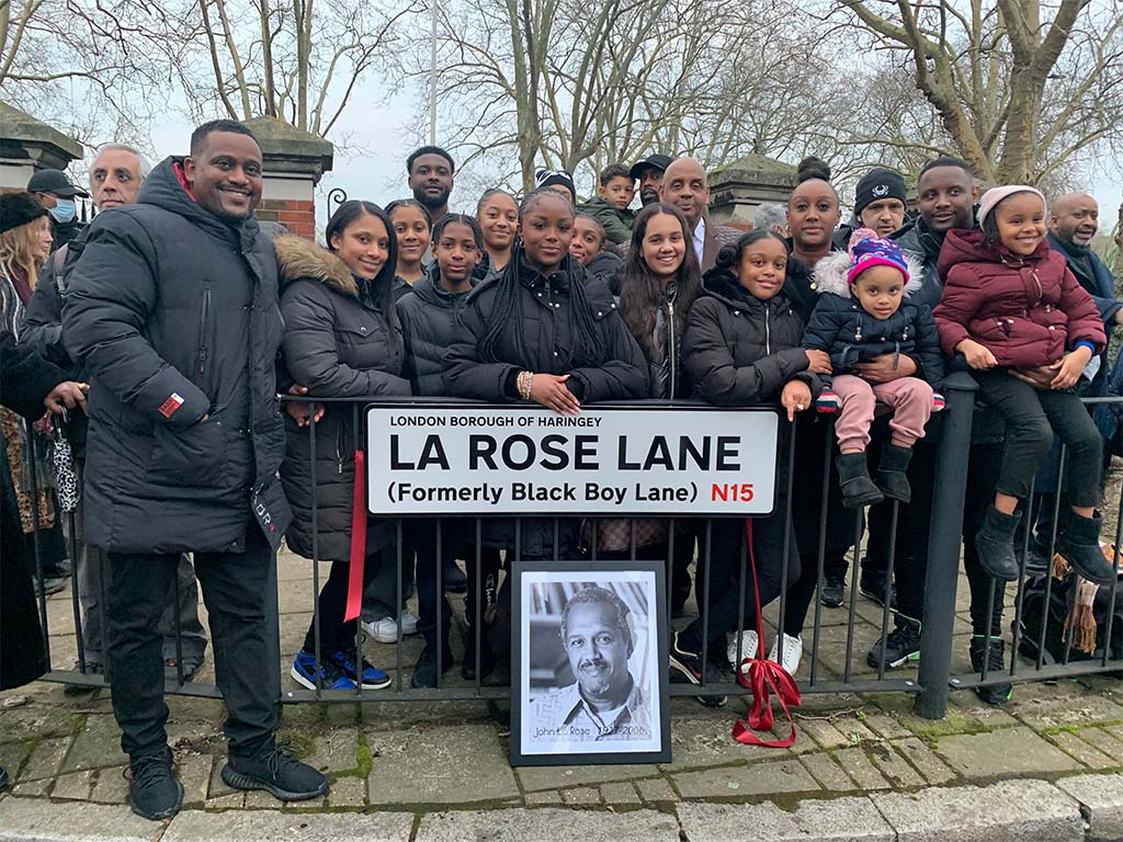 An image of a group of predominantly Black people, stood by the street sign for La Rose Lane.