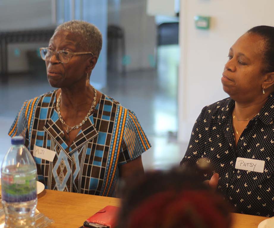 An image of two people sat at a table looking at something towards their right.