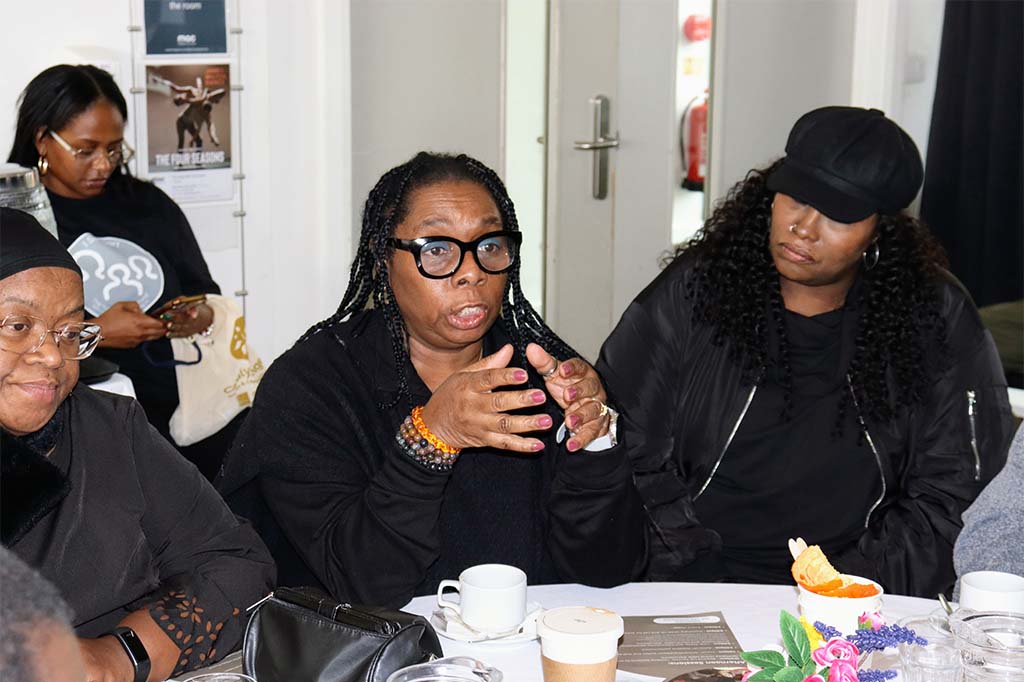 A group of Black people sat at a table talking.