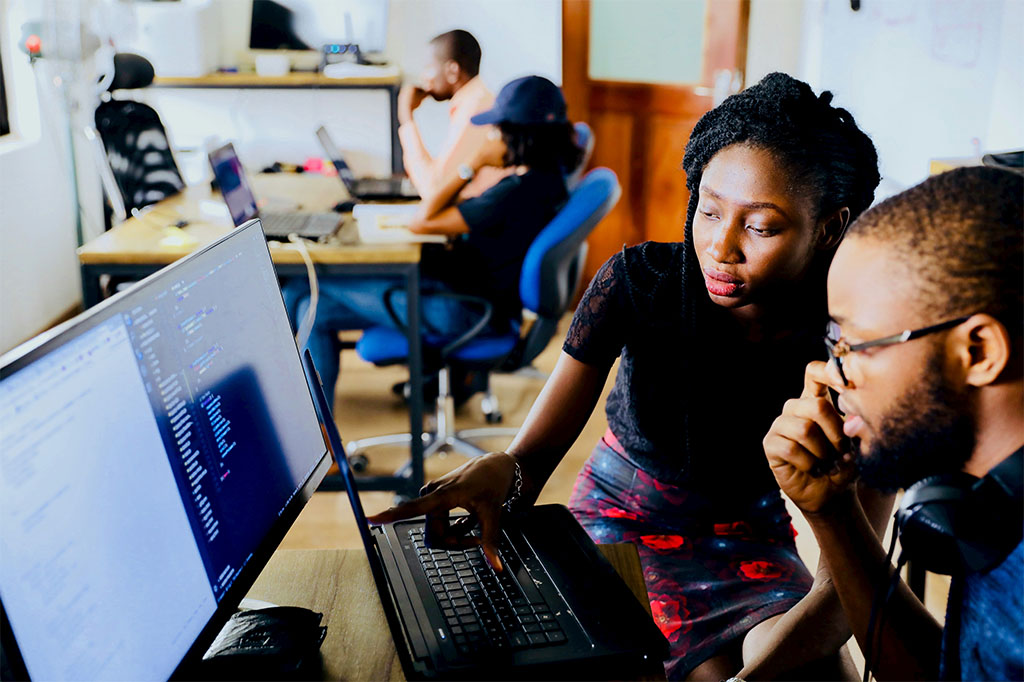 An image of two Black people sat in an office, working on a computer. Photo by Desola Lanre-Ologun on Unsplash